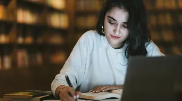 A young college student studies for finals in a library